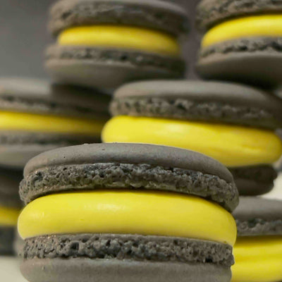 Stacked macarons with black cookies and yellow filling on a blurred background