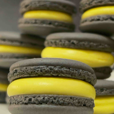 Macaron shells colored with activated charcoal and filled with curcumin-tinted cream – natural black and yellow macarons