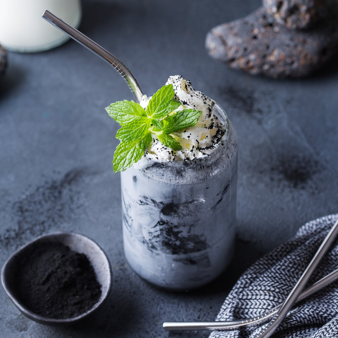 Minty milkshake with whipped cream and a straw on a dark surface
