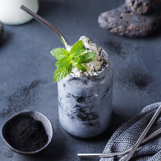 Minty milkshake with whipped cream and a straw on a dark surface
