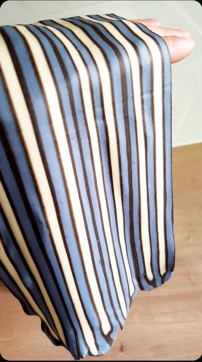 Striped fabric held by a hand on a pasta surface