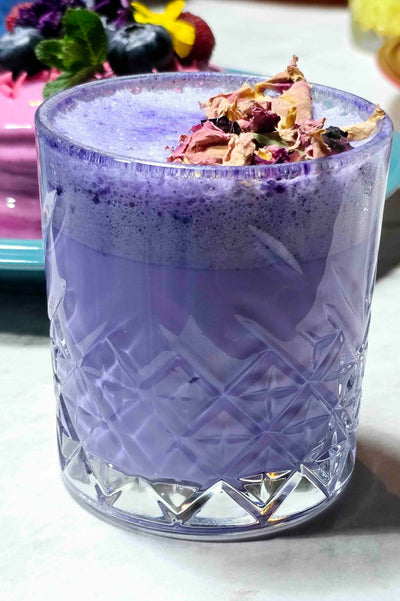 Purple drink in a textured glass with decorative elements on a white surface
