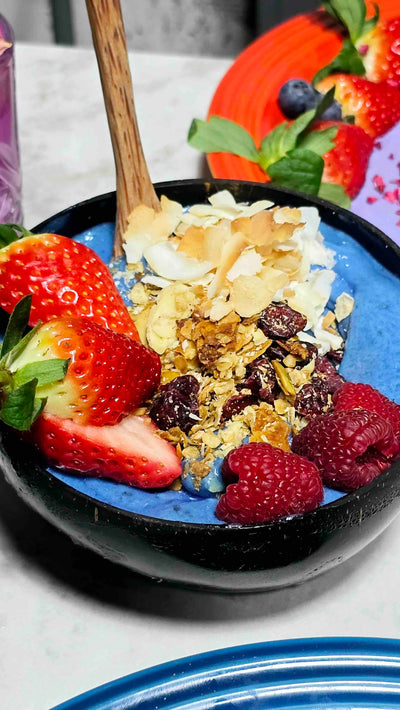 Yogurt bowl with berries and granola on a white plate
