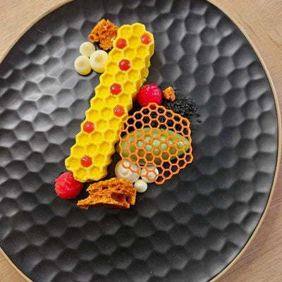 Colorful honeycomb-shaped dessert on a textured black plate