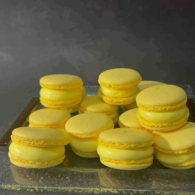 Stack of yellow macarons on a reflective surface with a dark background