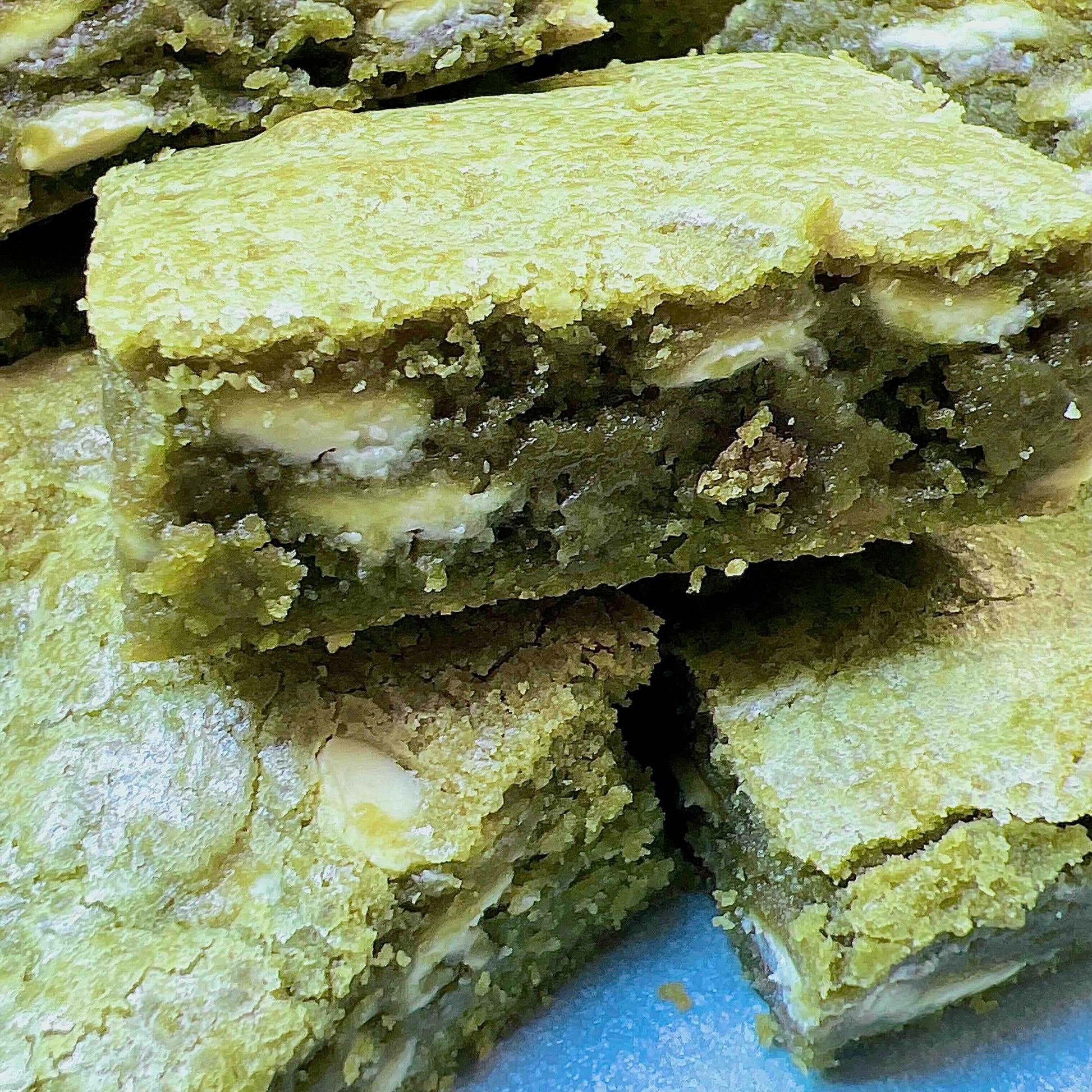 Close-up of green matcha cookie bars with white filling on a blue plate