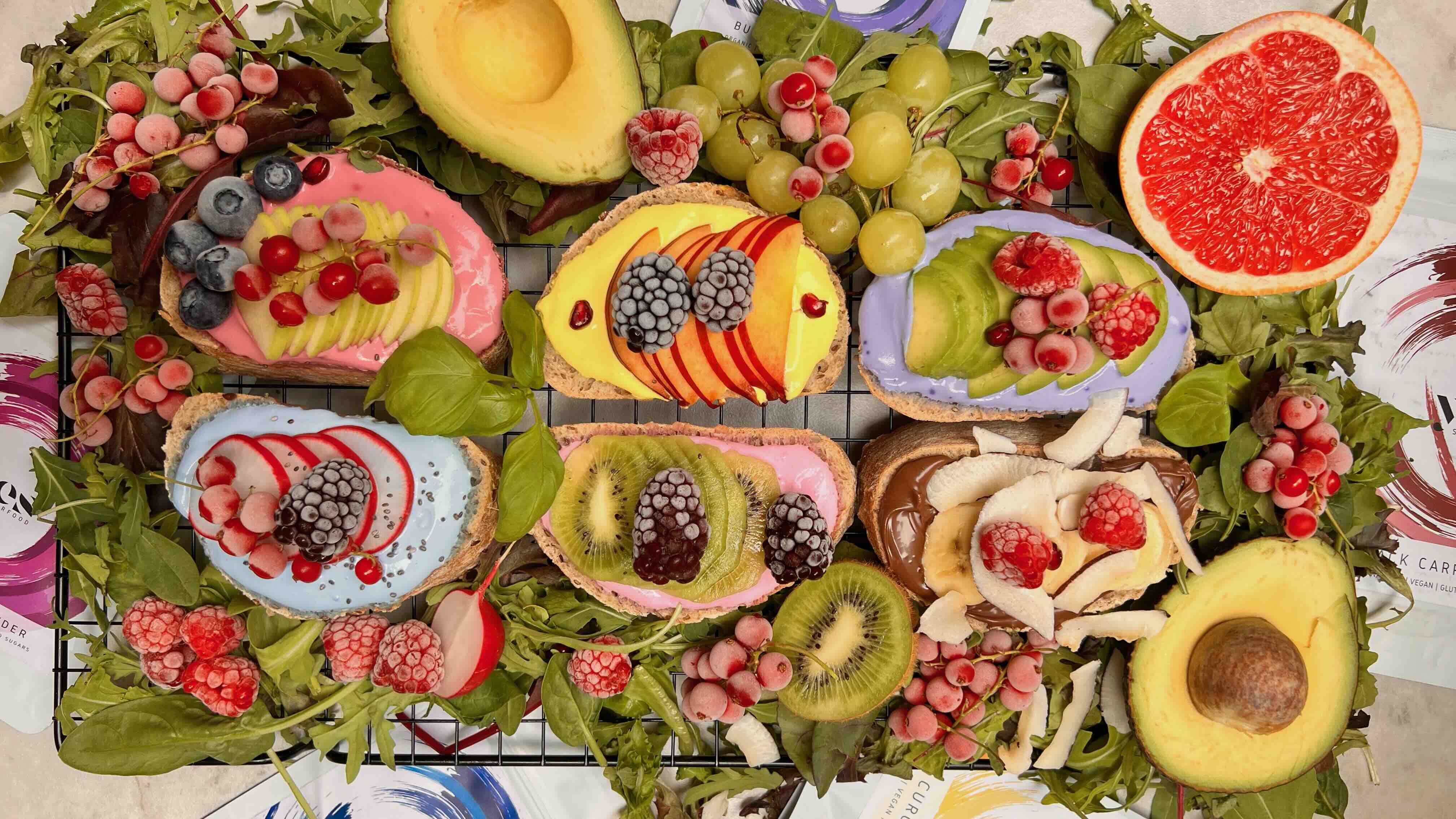 Assorted fruits and desserts on a cooling rack with green leaves.