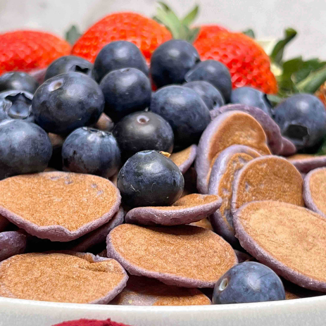 Mini pancakes colored with black carrot powder served with blueberries and strawberries – natural purple food coloring