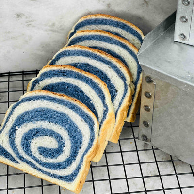 Sliced blue and white swirled bread on a cooling rack.