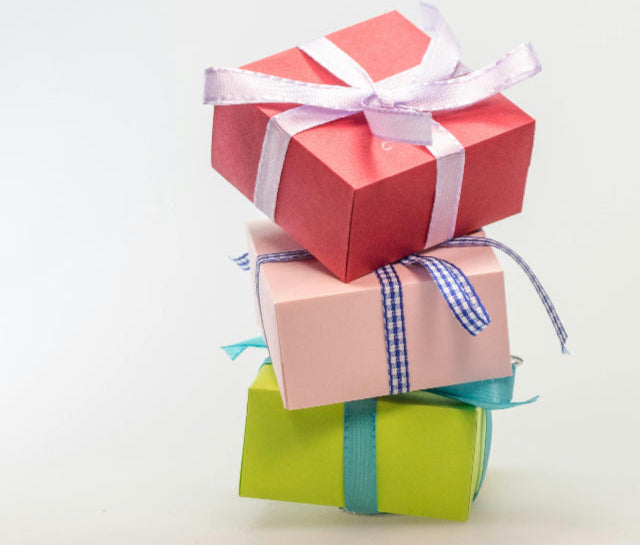 Stack of colorful gift boxes with ribbons on a light background