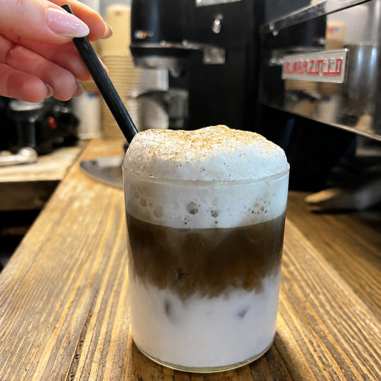 Layered iced hojicha latte with milk foam and roasted hojicha powder
